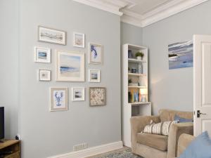 een woonkamer met een witte muur met foto's erop bij Sandgate Apartment in Sandgate