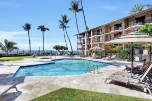 uma piscina em frente a um hotel com palmeiras em Oceanfront Penthouse with Loft em Kailua-Kona