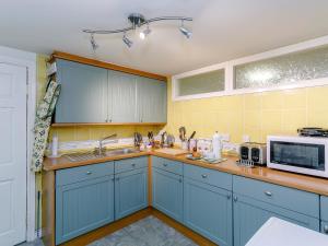 a kitchen with blue cabinets and a microwave at The Garden House-uk11837 in Dronfield