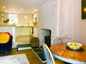 cocina y sala de estar con mesa y chimenea en Lemon Cottage en Bickington