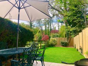 una mesa y sillas con una sombrilla en el jardín en Lemon Cottage en Bickington