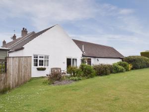 a white house with a fence and a yard at Prior Dene Cottage in Staintondale