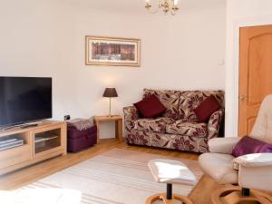 a living room with a couch and a flat screen tv at Alices Lodge in Ringwood