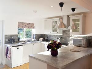 a kitchen with white cabinets and a vase of flowers on a counter at Alices Lodge in Ringwood