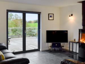a living room with a television and a sliding glass door at Thistlebank in Banknock