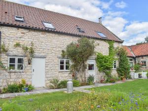 ein Steinhaus mit weißen Türen und einem Hof in der Unterkunft Fox Cover Cottage in Great Edston