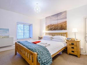 a bedroom with a wooden bed with a blue blanket at Pebble Cottage - Uk32243 in Aberdyfi