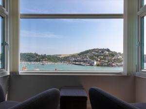 a window with two chairs and a view of a harbor at The Mews Apt 1 Newcomen Road in Dartmouth