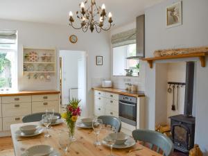 eine Küche mit einem Tisch mit Stühlen und einem Kronleuchter in der Unterkunft Elm Cottage in Whitwell