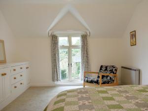 a bedroom with a bed and a chair and a window at Elm Cottage in Whitwell