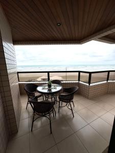 a balcony with a table and chairs and the ocean at Lindo apartamento de frente ao mar in Praia Grande