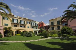 a row of buildings with palm trees and grass at Residence i Cormorani in Loano