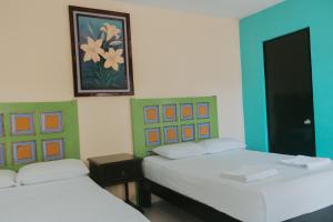 Habitación con 2 camas y una foto en la pared. en Hostal Tunich Naj & Hotel, en Valladolid