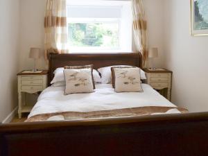 a bedroom with a bed with two night stands and a window at Prudhoe Mews in Alnmouth