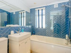 a blue tiled bathroom with a sink and a tub at Beach Retreat in Corton