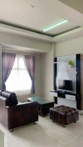 sala de estar con sofá y TV de pantalla plana en Newton Residence Apartment bm, en Bandung