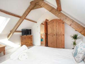a bedroom with a white bed and a wooden cabinet at The Shippon - Uk37467 in Berrynarbor