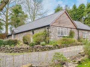 a stone house with a stone wall in front of it at Walkmill Lodge in Wentnor