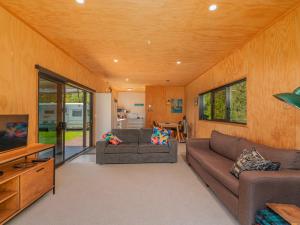 a living room with two couches and a tv at Whangapoua Hideaway - Whangapoua Bach in Whangapoua