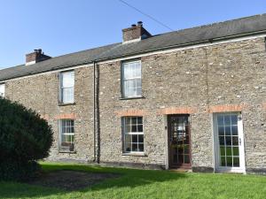 un ancien bâtiment en briques avec des fenêtres et une porte dans l'établissement Squirrel Cottage, à Wadebridge