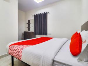 - une chambre avec un lit blanc et des oreillers rouges dans l'établissement Red Stone Hotels, à Hyderabad