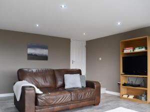 a brown leather couch in a living room with a television at Pathacres in Mochdre