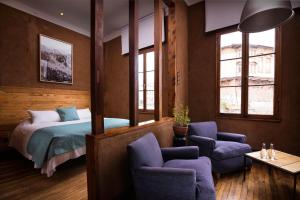 um quarto com uma cama, cadeiras e janelas em Fauna Hotel em Valparaíso
