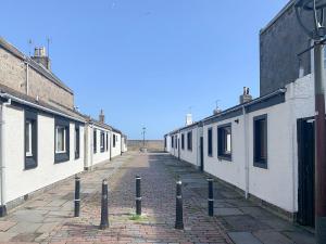 een lege straat met een rij witte gebouwen bij Footdee Cottage in Aberdeen