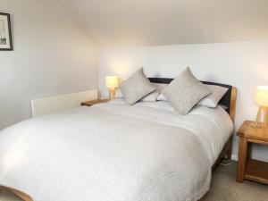 1 dormitorio con 1 cama blanca y 2 lámparas en Oak Cottage, en Clifton