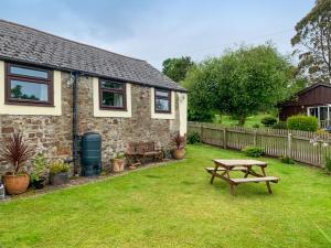 a stone house with a picnic table in the yard at Birdsong Cottage in Hartland