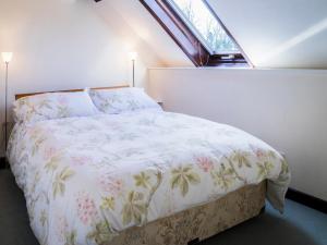 a bedroom with a bed with a white bedspread and a window at Bergerac Cottage in Uplyme