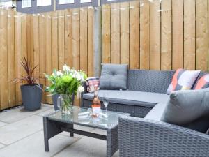 a patio with a couch and a table and a fence at Dragonfly Cottage in Beverley