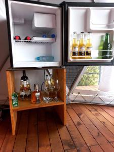 an open refrigerator with bottles and glasses on a table at Glamping hermoso amanecer in Guatavita
