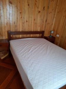 a bed in a room with a wooden wall at Cabañas encanto de Chovellen in Pelluhue