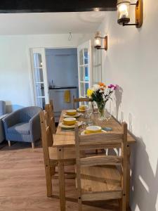 a wooden dining room table with chairs and flowers on it at The Brooks in Crowan