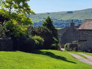 a stone house on a hill with a green yard at Lightfoot House in Redmire