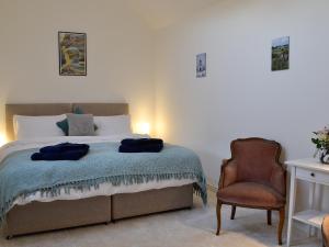 a bedroom with a bed with a chair and a chair at Straton Cottage in Saint Cyrus