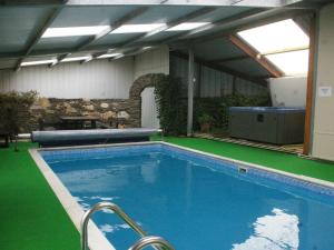 a large swimming pool with green flooring in a building at The Carthouse - Uk13184 in Cwm-Morgan