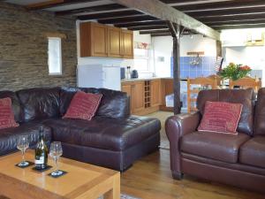 a living room with two leather couches and a table with wine glasses at The Carthouse - Uk13184 in Cwm-Morgan