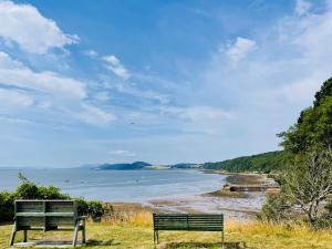 two benches sitting on a hill overlooking a beach at Bank Garden Cottage in Fortrose