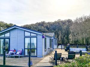 a blue tiny house with chairs and a patio at Ocean Retreat Lodge in Corton