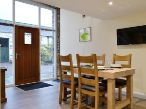 comedor con mesa, sillas y TV en Mary Rook Cottage - Uk1369, en Keswick
