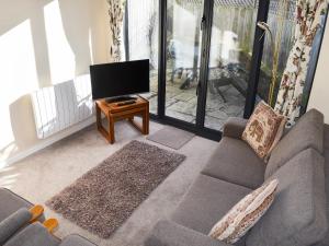 a living room with a couch and a flat screen tv at Retreat Cottage in Salcombe