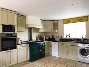 cocina con armarios verdes y blancos y lavavajillas en Brankley Cottage - E4712, en Dunstall