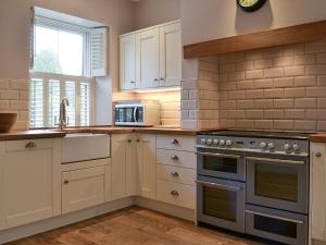 a kitchen with white cabinets and a stove top oven at Rowan House in Threlkeld