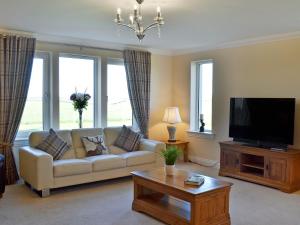 a living room with a couch and a flat screen tv at Wheatfield House in Kilmaurs