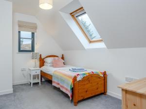a bedroom with a bed with a wooden frame and two windows at Cliff Cottage in Kalnakill