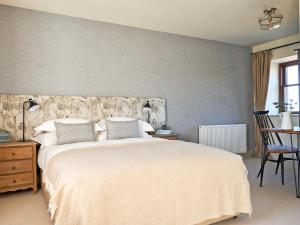a bedroom with a large white bed and a chair at Midcraigs in Kilchenzie