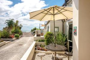 a patio with an umbrella and a table and chairs at Onetangi Beach Apartments in Onetangi