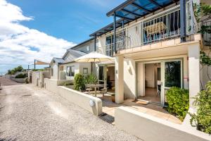 a house with a table and an umbrella on a street at Onetangi Beach Apartments in Onetangi